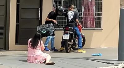 Mulher caída no chão e bandidos roubando a moto  Foto: Redes sociais