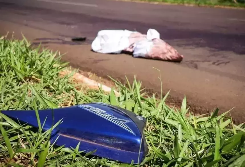 Corpo da vítima caído ao solo em segundo plano e, em primeiro, uma peça da moto que ele pilotava; Foto: Campo Grande News