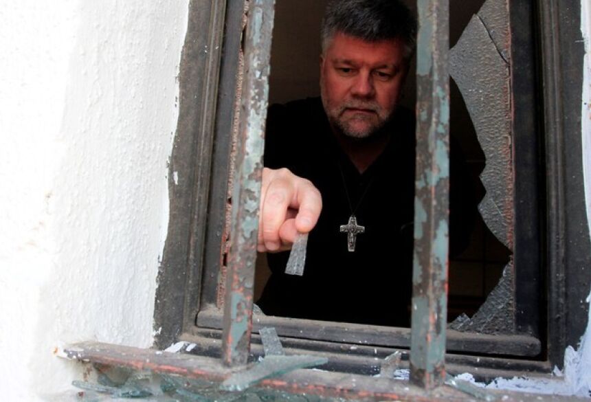 Homem remove cacos de vidro de janela de igreja atacada em Santiago do Chile, poucos dias antes da visita do papa ao país (Foto: Christian Iglesias/Reuters)