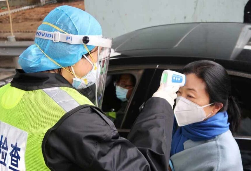 Coronavírus: oficial com máscara protetora verifica temperatura de passageiro em um pedágio entre Xianning e Wuhan, na China, em meio às restrições de circulação de pessoas, que tenta frear a expansão da doença — Foto: Martin Pollard/Reuters.