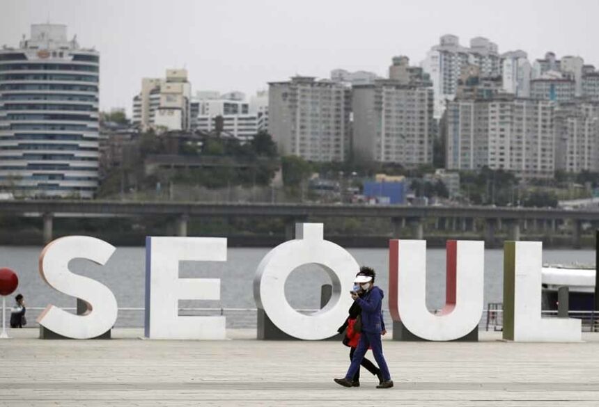 Visitantes com máscaras perto do rio Han na Coreia do Sul, neste domingo (19). Governo deve manter restrições, mas prepara relaxamento de algumas medidas — Foto: Lee Jin-man/AP